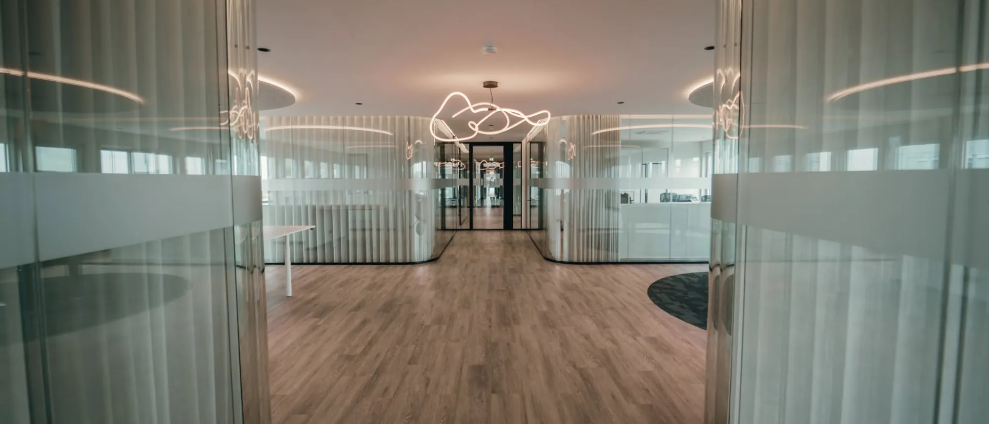 Flur im Mindbrain-Büro in Holzwickede mit runden Glaswänden und Lichtinstallation
